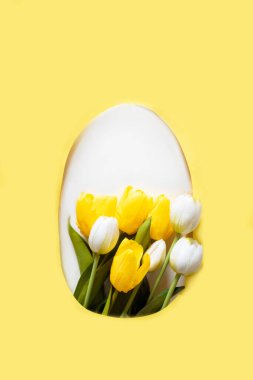 Sarı kağıtta lale çiçekleri olan yaratıcı Paskalya düzeni. Bahar doğası, Paskalya bayramı minimum konsepti. Yumurta şekli düz..