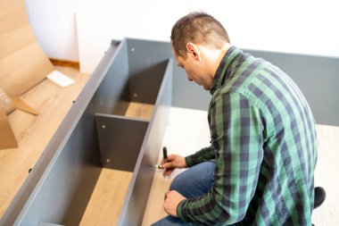 The man assembling new furniture at his home.