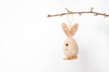 Bahar dallarının Paskalya ağacı cam bir vazoda beyaz arka planda pastel yumurtalarla doludur..