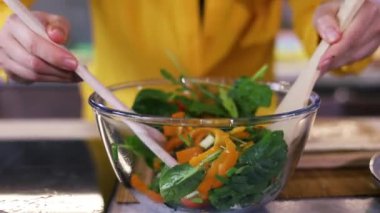 30 'lu yaşlardaki Asyalı kadın modern ev mutfağında durup sağlıklı sebze salatası hazırlıyor. Gülümsemeler sürecin tadını çıkarıyor. Tatmin olmuş ev hanımı müşterisi. Kolay ve taze organik gıda teslimatı konsepti.