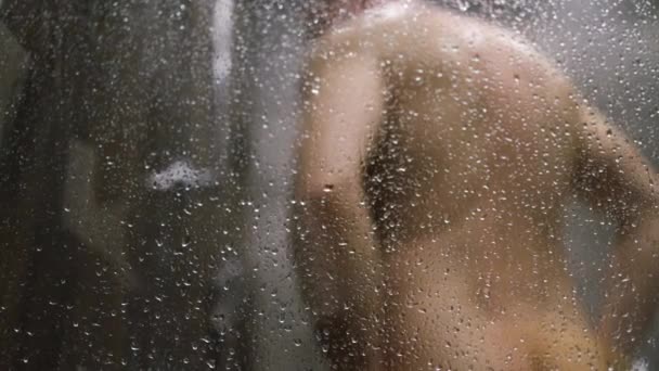 朝シャワーを浴びている男性 蒸気およびぼやけた人のボディが付いているぬれたシャワーのキャビン — ストック動画