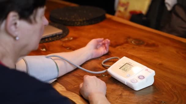 高齢の女性は 自宅で自分でデジタル圧力計で血圧と心拍数をチェックしています 高齢の女性は 健康を世話しています 健康と医療のコンセプト — ストック動画