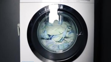 Çamaşır makinesinde renkli çamaşır yıkamak. Otomatik yıkama sistemi devrede. Dönüşümlü cam kapıdan çok renkli şeyler geçiyor. çamaşır yıkama