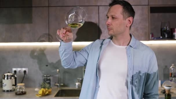 在家里的厨房里 男人们正在倒入一杯白葡萄酒 中年男人喝酒 在家里舒适的房间里品酒 微笑的中年男人的画像 — 图库视频影像