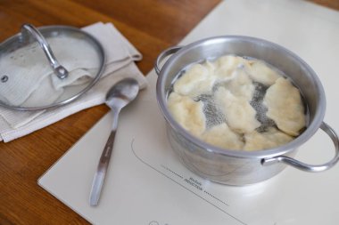 Cooking delicious dumplings in pot on cooktop