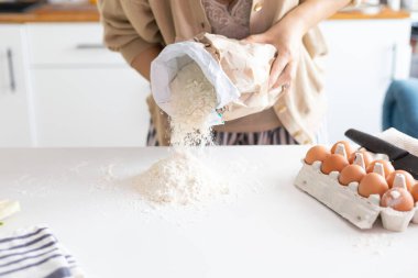 Tanınmayan kadın mutfak masasına un serpti. Yakından bakınca elleri hamur yoğurdu. Modern ev içinde Şükran Günü için bir fırın hazırlıyordu.