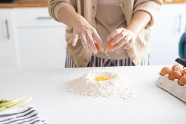 Hamur için yumurta kıran fırıncının yakın çekimi. Kadın mutfakta hamur tatlısı hazırlıyor..