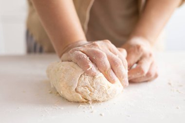 female hands skillfully kneading raw bread dough for homemade bread cooking. Bakery concept. Close-up. Preparation of the dough.