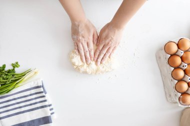 Mutfaktaki beyaz masada İtalyan Grissini için hamur yoğuran kadın..