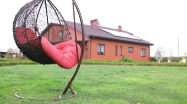 Yaz bahçesinde rahat bir hasır beyaz sandalye. Hafta sonu için rahat bir yer bahçede rahatla. Arka bahçede asılı hamak sandalyesi. Açık havada dinlenme kavramı.