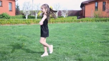 Küçük mutlu Ukraynalı kız yaz yeşili çimlerin üzerinde daireler çiziyor. Yaz parkında dans eden kız. Mutlu gülümseyen kız hayatın tadını çıkar..