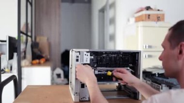 printer repair technician. A male handyman inspects a printer before starting repairs in a client's apartment.
