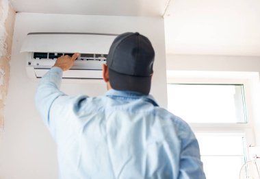 Erkek teknisyen içeride klimayı temizliyor..