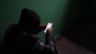 Karanlık, eski bir dairede cep telefonu kullanan üzgün bir gencin silueti. Yalnız yaşayan üzgün adam stresli, düşünceli, aile sorunları, stres, şiddet, depresyon konsepti..