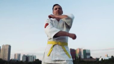 Kafkas sporcusu gün batımında çeşitli karate teknikleri uyguluyor..