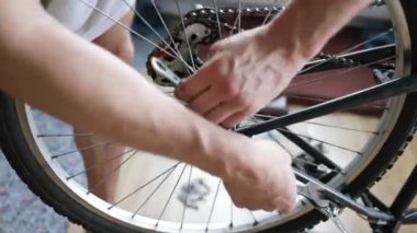 Tamirhanede bisiklet tamircisi bisiklet tekerleğini tamir ediyor. Velocipede servisi. Tamirci erkek bisikletçi atölyede bisiklet tekerleğini tamir ediyor. Teknisyen bisiklet parçalarını tamir ediyor. İş yerindeki tamirci.