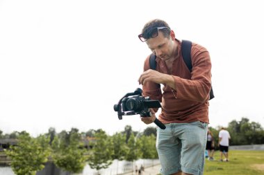 videografi, film yapımı ve yaratıcılık kavramı - modern DSR kameranın 3 eksenli titreşim dengeleyicisi üzerinde kapalı gökyüzü arkaplanı üzerinde erkek ellerde.