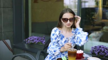 Anne ve genç kız yaz terasında kafede ferahlatıcı içkiler içerler. Dişi çocuk, annesiyle şehirde vakit geçirmekten hoşlanıyor..