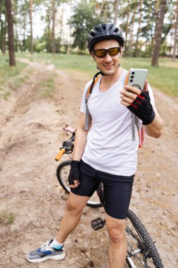 Yoğun egzersizden sonra dinlenen bir sporcu. Dinlenirken Smartphone kullanan bisikletçi. Akıllı Telefon ve Arkadaşlarla Mesaj Kullanan Atletizm Sporcusu Bisiklet Sürdükten ve Sosyal Ağ 'da Sohbet ettikten Sonra Dinleniyor