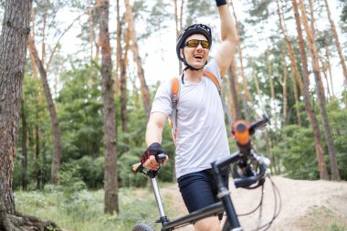 Heyecanlı erkek Mountainbiker güneşli bir ormandaki.