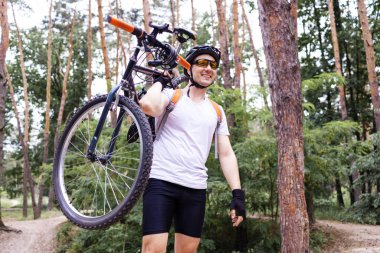 Güneşli bir günde ormandaki Bisiklet taşıyan erkek dağ bisikletçinin.