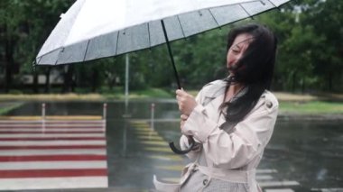 Yağmurlu bir günde, elinde şemsiyeyle yağmurun altında tek başına yürüyen bir kadın. Yavaş çekim..