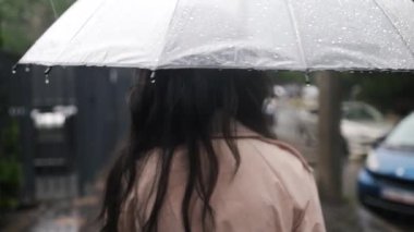 Yağmurlu bir günde, elinde şemsiyeyle yağmurun altında tek başına yürüyen bir kadın. Yavaş çekim..