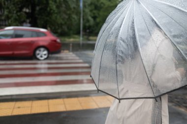 Şemsiyesini tutan kadın yağmurlu bir günde yağmurun altında yürüyor..