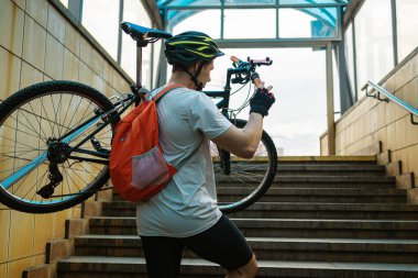 Yeraltından bisikletle çıkan genç bir adam. Motosikleti Metro 'dan çıkarıyorum. Taşıma Konsepti.