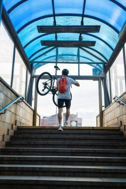 Yeraltından bisikletle çıkan genç bir adam. Motosikleti Metro 'dan çıkarıyorum. Taşıma Konsepti.