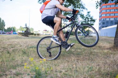 Bisiklet kıyafetleri, miğfer ve güneş gözlüğü takmış bisiklet yolunda bisiklet süren mutlu bir adamın portresi. Aktif sporcu imajı.