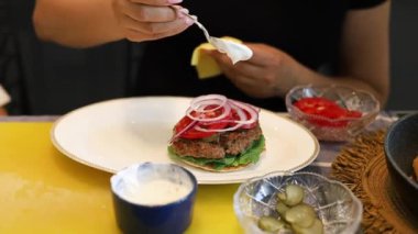 Anne ve çocuk mutfakta ev yapımı hamburger yiyorlar. Mutlu aile evde çizburgerleri birlikte yiyor..