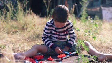 Bir çocuk yere plastik bir araba monte ediyor..