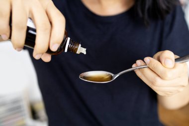 Kavanozdan alınan tıbbi şurup kaşığa dökülür. İlaç, tedavi. Öksürük şurubu.