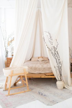 Yatak odasında parlak bir Scandi tarzı iç mekan. Bir gölgelik, keten bir yatak ve jüt bir halı. Tam boy pencereler. Dikey çekim. 