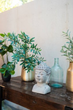 Tütsülenmiş Buda kafası ve vazoda bitkiler. Budizm dini. Ahşap masada dekoratif Buda heykeli. 