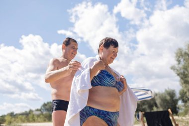 Mayolu yaşlı çift güneşli yaz günlerinde nehrin kıyısında güneşleniyorlar..