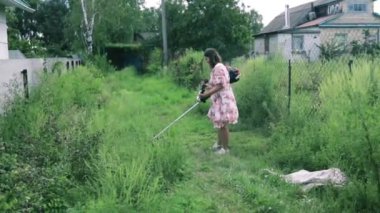 Beyaz kadın arka bahçesinde çim biçme makinesiyle çim biçiyor.