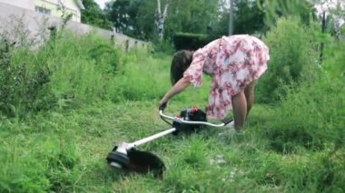 Beyaz kadın arka bahçesinde çim biçme makinesiyle çim biçiyor.