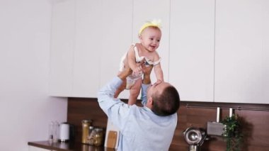 Genç beyaz anne-baba ve yeni doğmuş bebek evde mutfakta oynuyorlar. Çocuk yetiştirme kavramı.