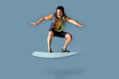 Sportif enerji erkek wakeboardçu çeşitli ekstrem numaralar yapıyor ve mavi arka planda izole bir şekilde atlıyor.. 