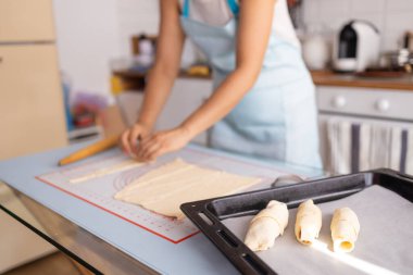 Evde klasik kruvasan üretiyor. Kadın daha fazla pişirmek için hamuru rulolara çeviriyor. Fransız hamur işleri.