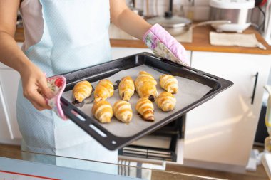 Open oven on a hot baking sheet, baked goods, close-up. Homemade croissants, puff pastry sausage, bun recipe.