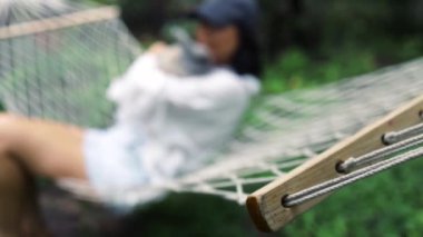 Asyalı kız Paskalya tavşanıyla yaz bahçesinde hamakta yatıyor. Evcil tavşanı olan kadın sakin ve sakin..