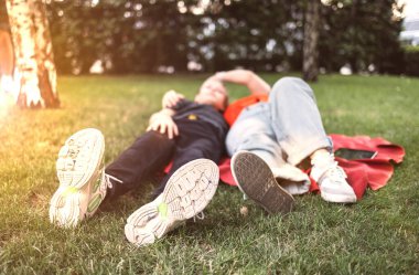 Neşeli anne ve oğul çimenlerde uzanıp yaz bahçesinde dinleniyorlar.