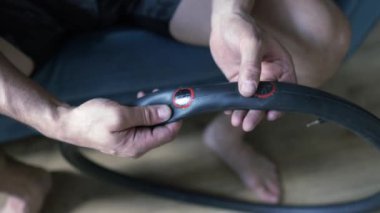 Bir tamircinin yakın çekimi elinde lastik bir yama tutar ve tekerlek iç tüpündeki deliği kapatır. Elektrikli scooter tekerleği için lastik lastiğin değiştirilmesi. Tekerlekler atölyede sökülüp onarılıyor