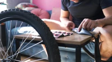 Bisiklet tamircisi tekerleği tamir ediyor. Evde dağ bisikleti tamir eden bir adam. Patlak bisiklet lastiğine el yaması yerleştiriyorum..