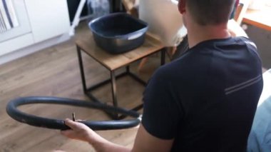 Bisiklet tamircisi tekerleği tamir ediyor. Evde dağ bisikleti tamir eden bir adam. Patlak bisiklet lastiğine el yaması yerleştiriyorum..