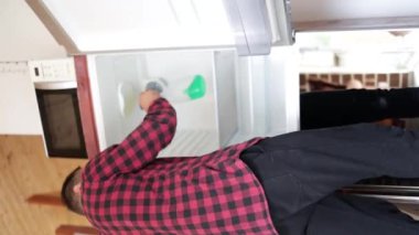 Buzdolabının içini temizleyen adam. Temiz ev, kişisel koruma ekipmanları, antibakteriyel temizlik..