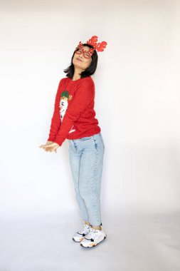 Noel ve Yeni Yıl konsepti. Kırmızı kazaklı mutlu Asyalı kız ve beyaz arka planda Noel bandı..